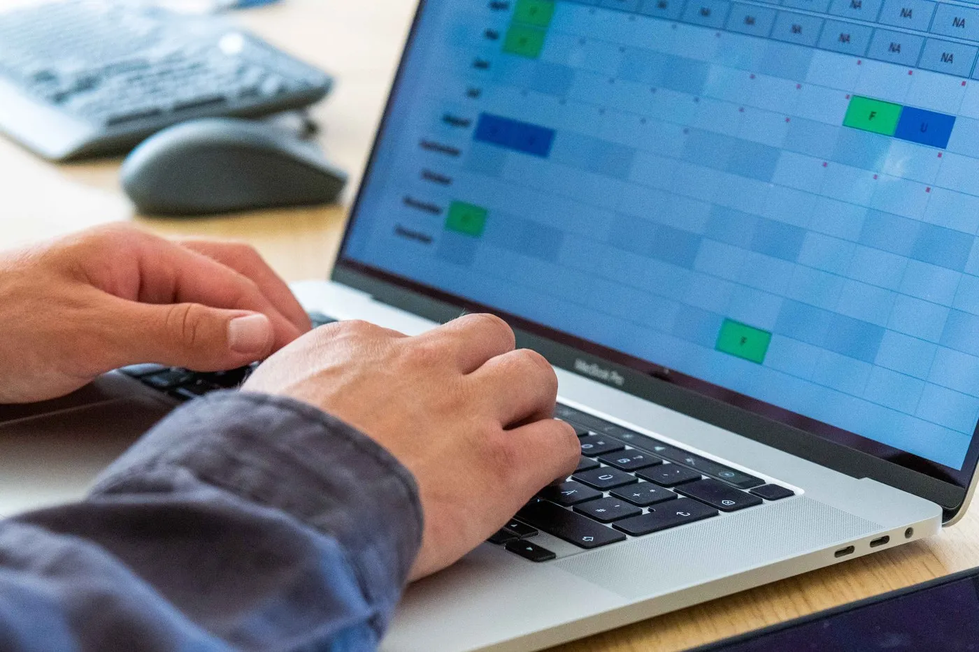 Mitarbeiter plant Dienste in der Timework Software am Laptop, farbig markierter Dienstplan mit Frei- und Urlaubstagen am Bildschirm