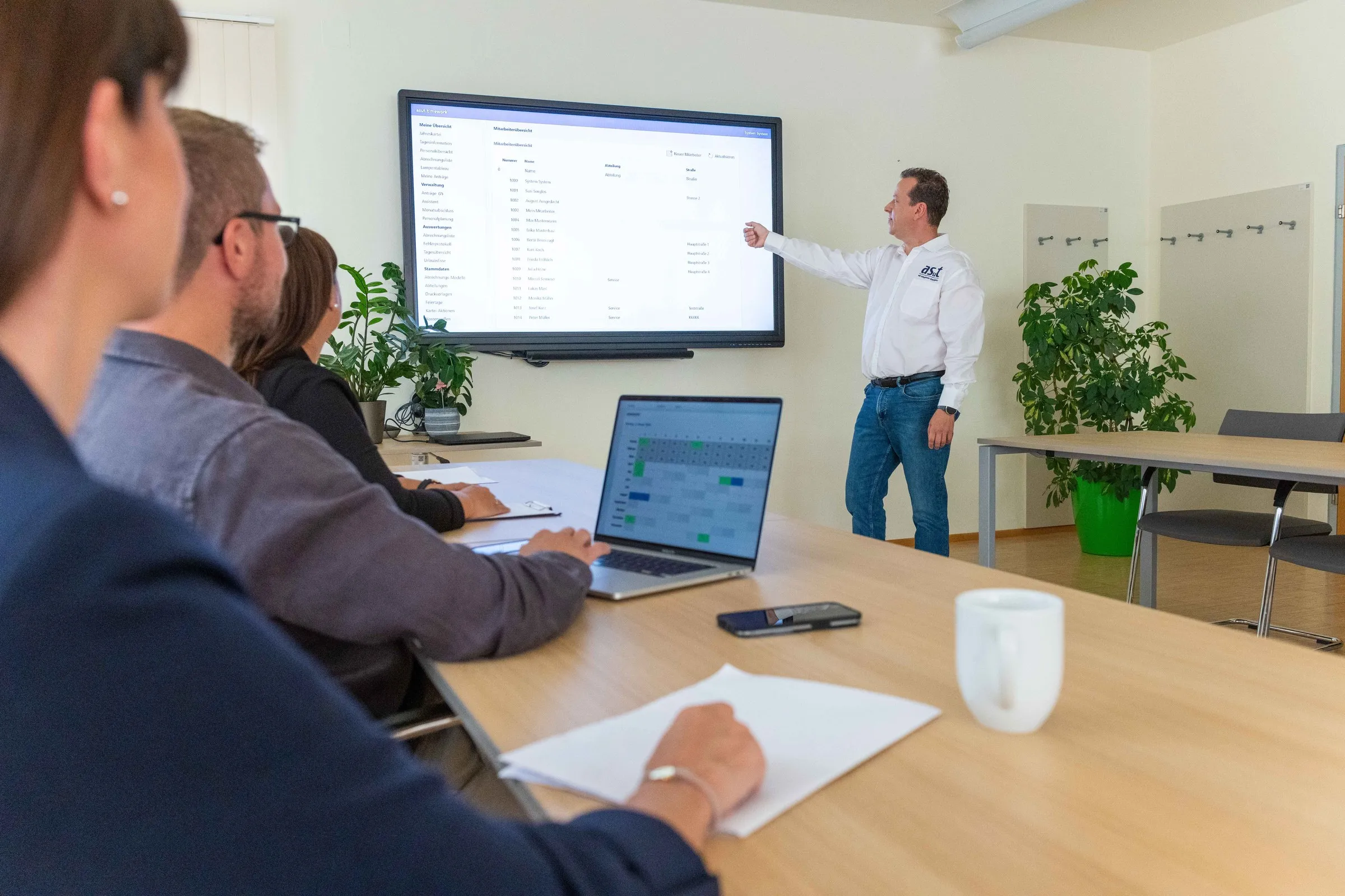 Team verfolgt eine Timework Produktschulung zur Dienstplanung, ein asut Berater erklärt die Personalplanung, im Vordergrund ein Laptop mit farbigem Dienstplan